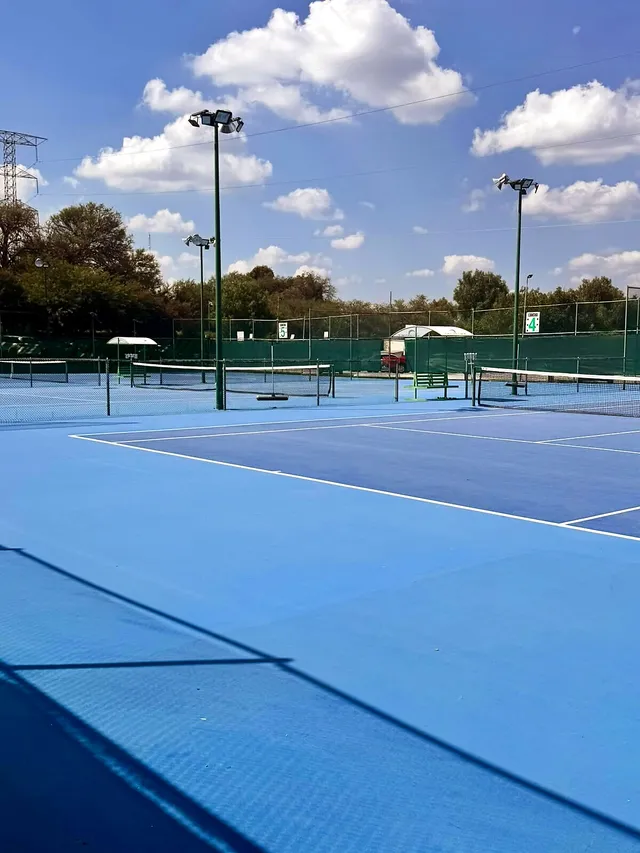 Cancha de tenis azul al aire libre con iluminación